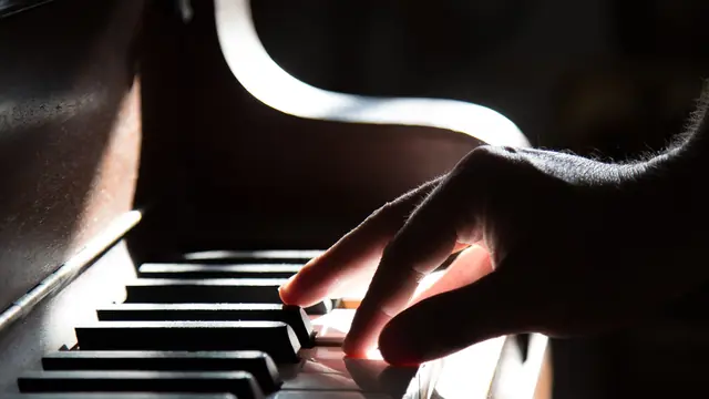 Accords au piano — main jouant un accord dans une lumière douce