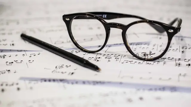 Accords au piano — feuille de musique, stylo et lunettes sur un bureau